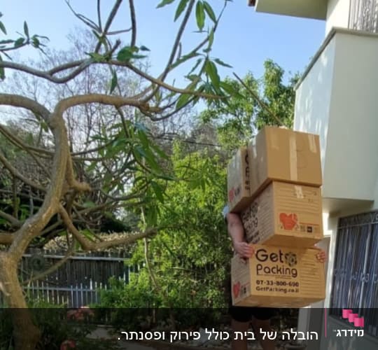 אדם נושא שלוש קופסאות קרטון גדולות בחוץ